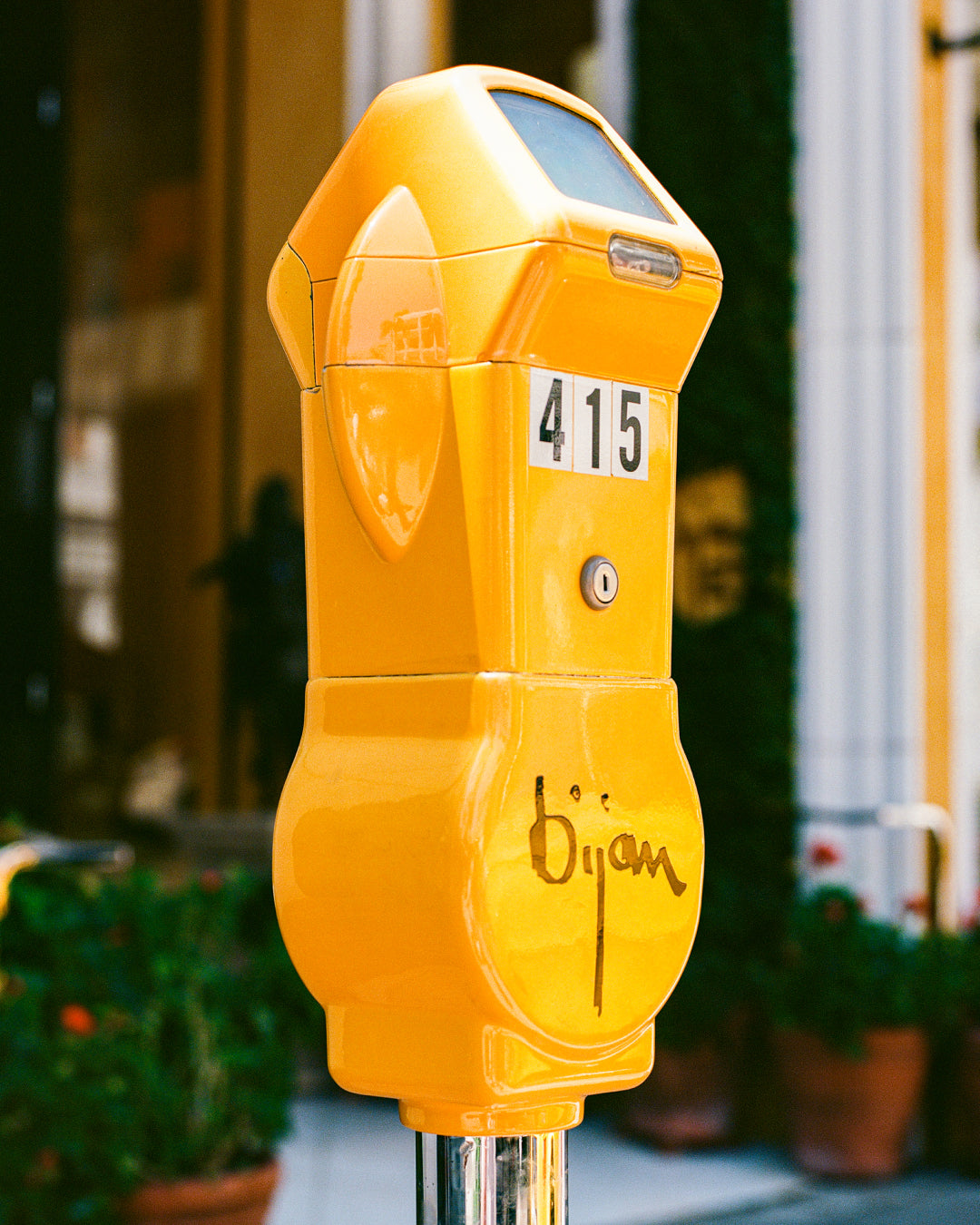 a yellow parking meter sitting on the side of a street