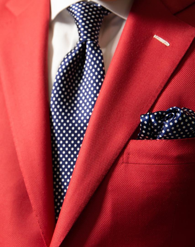 Image of red tailored suit with navy tie and white polka dots