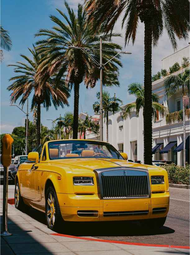 a yellow rolls royce parked on the side of the road