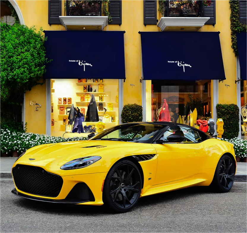 a yellow sports car parked in front of a store